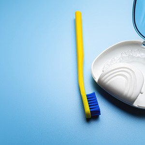 An Invisalign tray in a carrying case next to a toothbrush